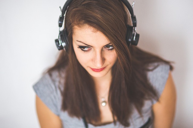 A young woman with long dark hair wears a set of headphones.